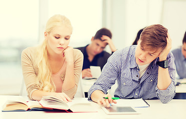 Image showing tired students with tablet pc, books and notebooks