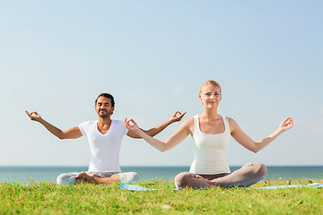 Image showing smiling couple making yoga exercises outdoors