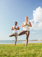 Image showing smiling couple making yoga exercises outdoors