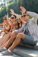 Image showing group of smiling friends sitting on city street