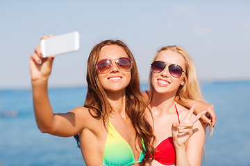 Image showing two smiling women making selfie on beach