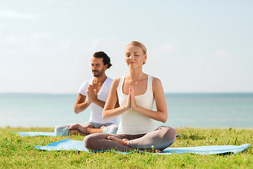 Image showing smiling couple making yoga exercises outdoors