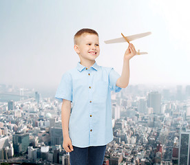 Image showing smiling little boy holding a wooden airplane model