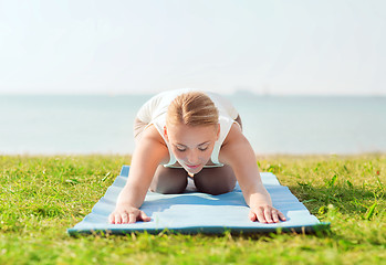 Image showing young woman making yoga exercises outdoors