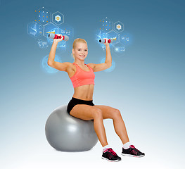 Image showing woman with dumbbells sitting on fitness ball