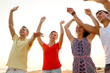 Image showing smiling friends dancing on summer beach