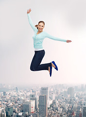 Image showing smiling young woman jumping in air