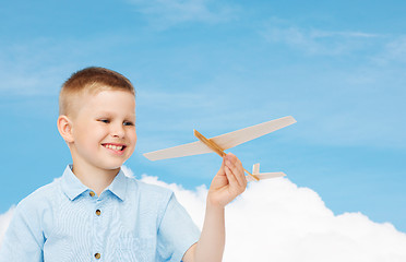 Image showing smiling little boy holding a wooden airplane model