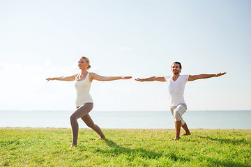 Image showing smiling couple making yoga exercises outdoors