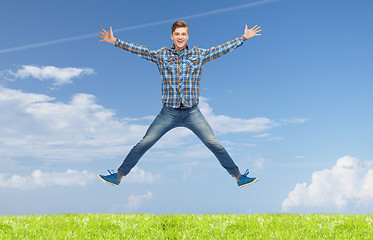 Image showing smiling young man jumping in air