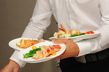 Image showing Waiter holds plates with lobsters