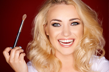 Image showing Laughing beautiful woman applying blusher