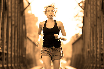 Image showing Active female athlete running on railaway tracks.