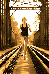 Image showing Active female athlete running on railaway tracks.