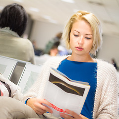 Image showing Woman reading a magazine while waiting.