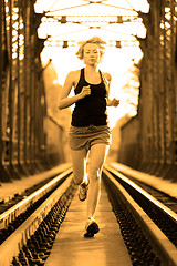 Image showing Active female athlete running on railaway tracks.