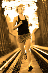 Image showing Active female athlete running on railaway tracks.