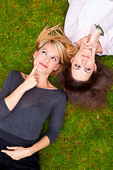 Image showing Two thoughtful girls lying in the grass