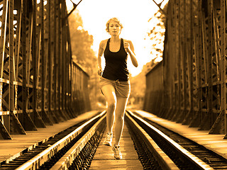 Image showing Active female athlete running on railaway tracks.