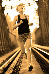 Image showing Active female athlete running on railaway tracks.