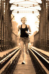 Image showing Active female athlete running on railaway tracks.