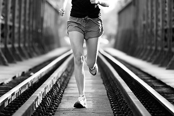 Image showing Active female athlete running on railaway tracks.