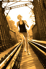 Image showing Active female athlete running on railaway tracks.