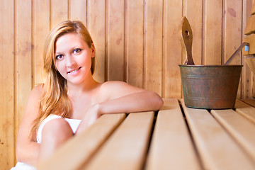 Image showing Lady relaxing in traditional wooden sauna.