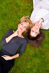 Image showing Two thoughtful girls lying in the grass