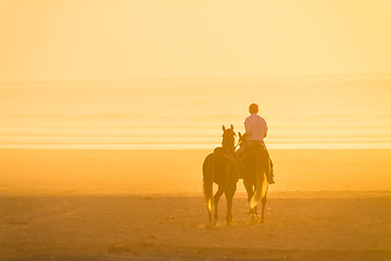 Image showing Horse riding on the beach at sunset.