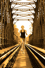 Image showing Active female athlete running on railaway tracks.