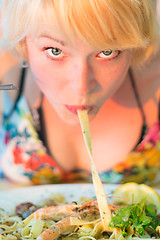 Image showing Woman eating seafood noodles.