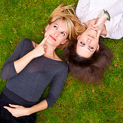 Image showing Two thoughtful girls lying in the grass