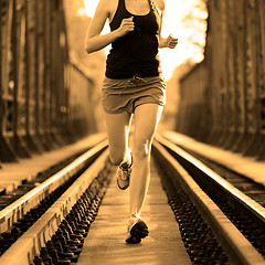 Image showing Active female athlete running on railaway tracks.