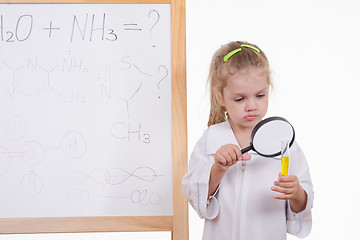 Image showing Chemist examines fluid, standing at the blackboard