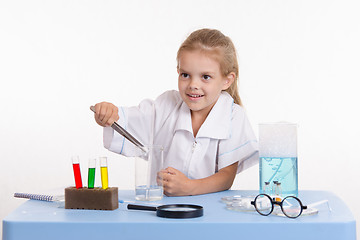 Image showing Girl throws a piece of reagent into flask in chemistry class