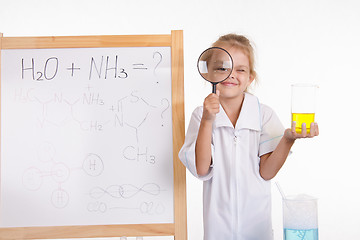 Image showing Girl chemist flask and magnifying glass at the blackboard