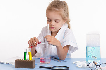 Image showing Schoolgirl pouring red liquid a flask in chemistry class