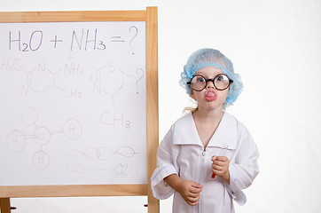 Image showing Girl chemist at the blackboard showing tongue