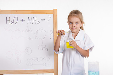 Image showing Girl shows chemical experience standing at the blackboard