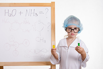Image showing Chemist girl in points and with two tubes at board