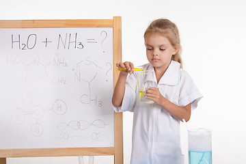 Image showing Girl pours liquid from a test tube into flask standing at blackboard