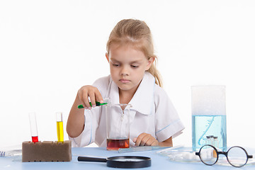 Image showing Chemist pours green liquid in a flask