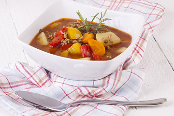 Image showing Hearty Stew in Bowl and Spoon on Plaid Dish Towel