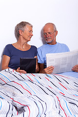 Image showing Senior Couple with Tablet and Newspaper in Bed