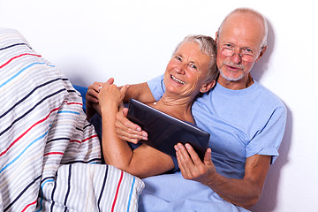 Image showing Senior Couple with Tablet and Newspaper in Bed