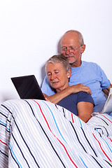 Image showing Senior Couple with Tablet and Newspaper in Bed