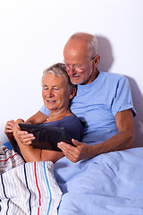 Image showing Senior Couple with Tablet and Newspaper in Bed