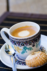 Image showing Cup of freshly brewed tea and a cookie