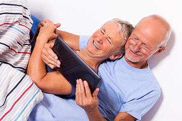 Image showing Senior Couple with Tablet and Newspaper in Bed